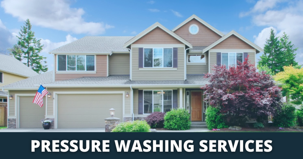 Two-story home with tan siding and brown trim, showcasing pressure washing services. An American flag hangs from the garage, with lush landscaping and a blue sky backdrop.