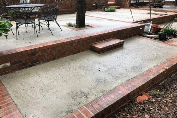 A clean concrete patio sits between low red brick walls.