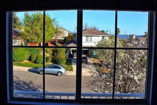 A clear window overlooks neighboring houses and a parked car.