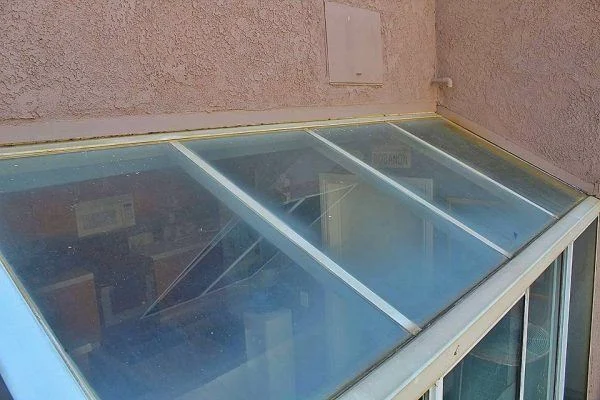 Cloudy glass panels cover a conservatory beside a stucco wall.