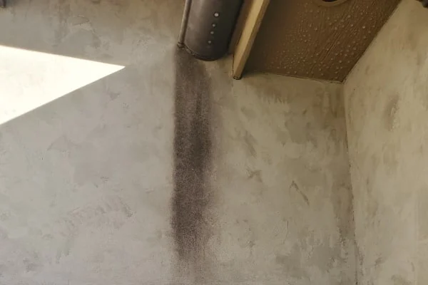 A dark vertical streak runs down a wall beneath roof beams.