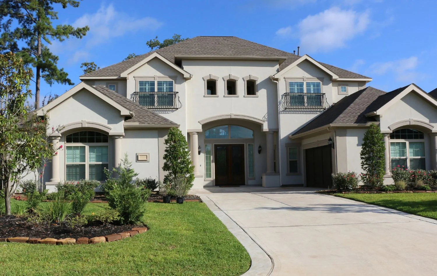 A curved driveway leads toward a large two story house.