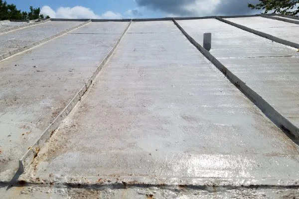 Light roof panels slope past a small vertical roof vent.