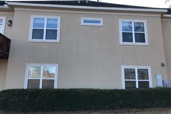 A beige building has evenly colored walls around its windows.