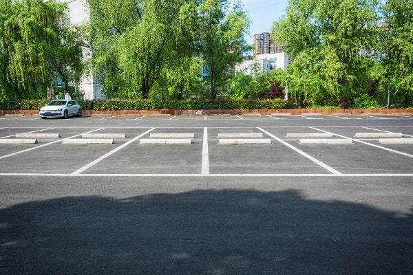 Empty parking lot with fresh pavement markings on a sunny day, highlighting the need for parking lot power sweeping to maintain cleanliness and visibility.
