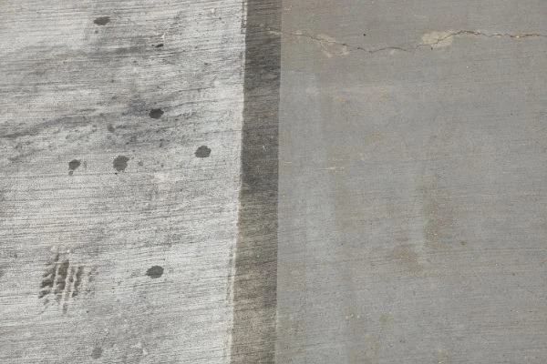 A straight boundary separates dark and light areas of concrete.