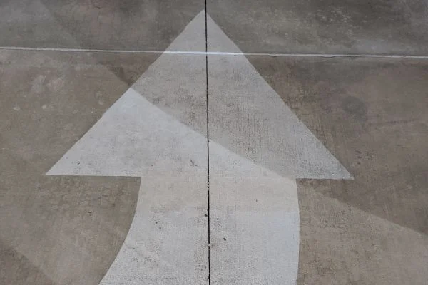 A large white directional arrow marks a concrete pavement surface.