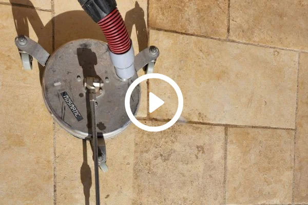 A video play symbol overlays a surface cleaner against stone.