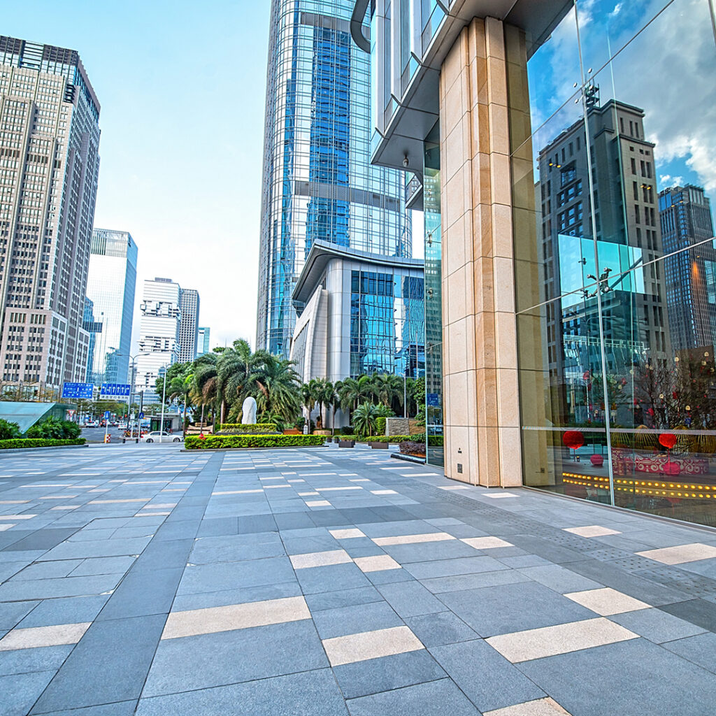 Modern city street with tall skyscrapers and palm trees, showcasing a clean, well-maintained commercial area. Ideal for illustrating the importance of commercial power washing in urban settings.